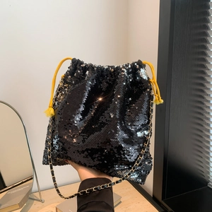 Detail showing the black sequined bucket bag with a yellow drawstring and gold chain strap