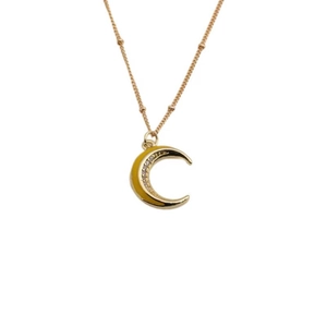 Collana con luna crescente dorata con zirconi scintillanti e catena a sfere su bianco