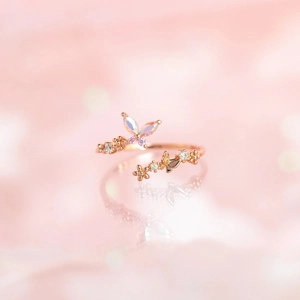 Detail of rose gold butterfly ring with opal texture and zircons on pink background