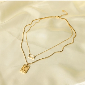 Detail of double-layer gold sun moon pendant necklace on soft beige silk background