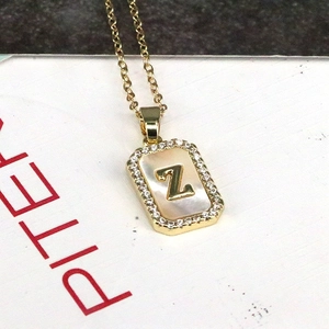 Close-up of 18K gold rectangular pendant with shell inlay and cubic zirconia letter Z