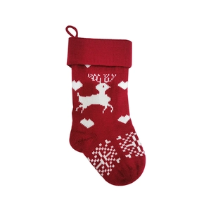 Detail of red knit Christmas stocking with white reindeer and snowflake jacquard patterns