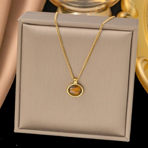 Élégant collier en acier inoxydable doré avec pendentif rond en aventurine sur un coffret