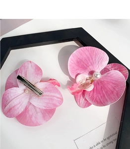 Detail of pink orchid hair clips with pearls and metal clips on a white surface