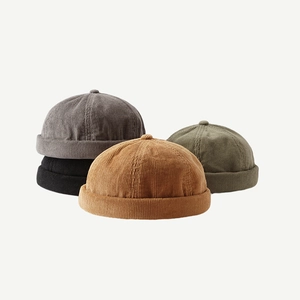 Detailed stack of corduroy skull caps in grey, black, brown and army green colors