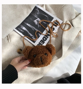 Detail of brown plush bear crossbody bag with woven strap on a beige suit