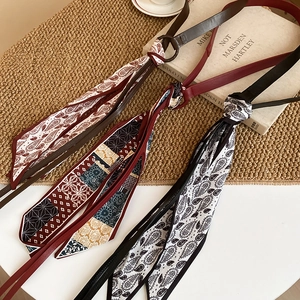 Close-up of vintage silk scarf waist chains with leather straps in colorful patterns