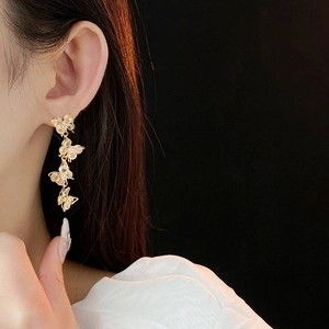 Macro shot of gold butterfly tassel earrings with sparkling cubic zirconia on a model