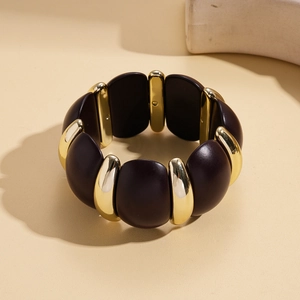 Close-up of retro acrylic and gold metal elastic bracelet with dark resin spheres