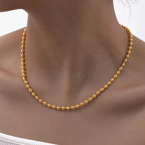 Close-up of golden beaded chain necklace on model neck for daily layering jewelry