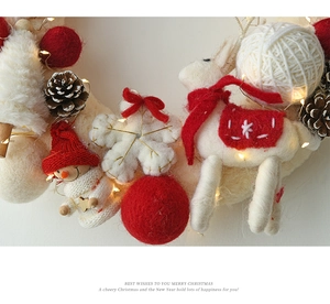 Detail view of wool felt Christmas wreath with reindeer, pine cones and LED lights