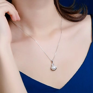 Elegant white pearl pendant necklace with diamond accents and silver chain on female model