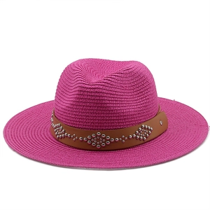 Detail of rose red straw hat featuring a brown faux leather band with silver metal studs