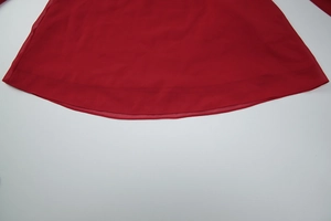 Détail de l'ourlet en mousseline rouge avec texture en maille délicate et drapé fluide
