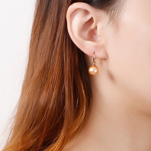 Élégantes boucles d'oreilles perles en or rose portées par un mannequin style épuré