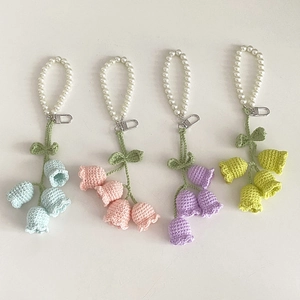 Detailed macro view of handmade crochet lily of the valley keychains with pearl charms