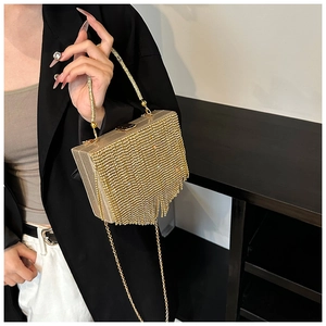 Detail of luxury gold evening clutch bag with cascading rhinestone fringe and metallic handle