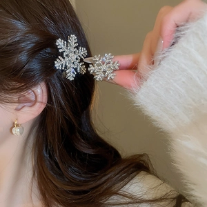 Close-up of sparkling snowflake hair clips and heart earrings on a woman's soft white sweater