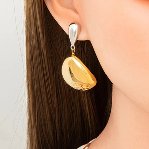 Close-up of elegant two-tone gold and silver leaf-shaped earrings worn by a model