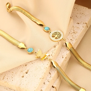 Detail of 18K gold butterfly and tree of life charms on turquoise beaded snake chains