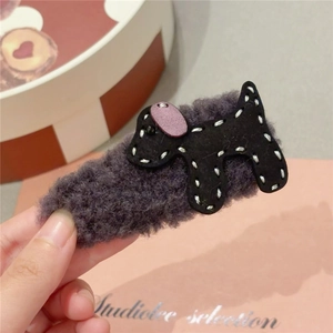 Detail of plush black puppy hair claw with purple ears and white stitching accents