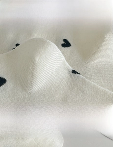 Detail of white cotton socks with black hearts showing elastic cuff and 3D heel design