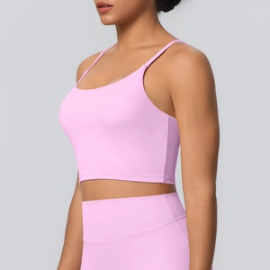 Détail d'un haut de yoga rose à fines bretelles et d'un legging taille haute sous lumière douce