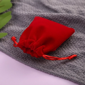 Macro shot of red velvet drawstring pouch with soft fabric texture and matching red cord