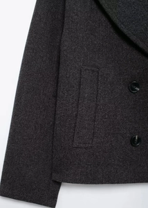 Detail view of dark grey wool blend coat showing double-breasted buttons and fabric texture