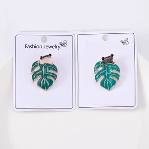 Close-up of two enamel frog pins on leaves showcasing fine metal craft and vibrant colors