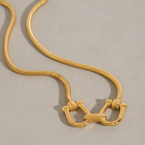 Detailed macro view of a gold-plated snake chain featuring a classic horsebit buckle link