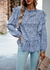 Dettaglio di una camicetta blu a fiori a maniche lunghe con eleganti spalle a balze e volant