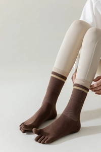 Detailed shot of brown cotton five-finger yoga socks with striped cuffs and non-slip sole