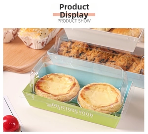 Close-up of clear lid paper box holding two egg tarts on a rustic wooden tray