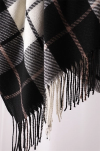 Close-up of black and white plaid scarf featuring woven cashmere-like texture and fringes