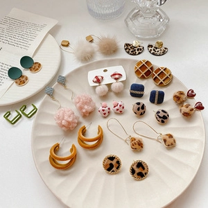 Close-up of leopard print and velvet geometric earrings set in a white porcelain bowl
