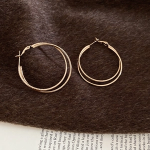Detail of gold double hoop earrings with one polished and one frosted textured metal ring