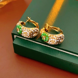 Macro detail of vintage gold hoop earrings with green beads and white pearls