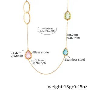 Detail van lange ketting met gefacetteerde glasstenen en gouden roestvrijstalen ringen
