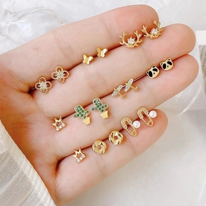 Macro shot of gold-plated stud earrings in various shapes held in a hand for scale