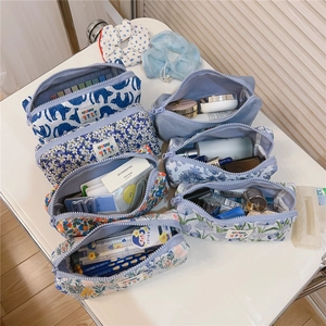 Detailed top view of various blue floral and pattern zipper pouches for stationery or makeup
