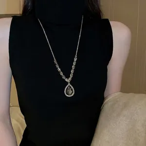 Collier doré luxueux avec une grande pierre grise en forme de poire et accents brillants