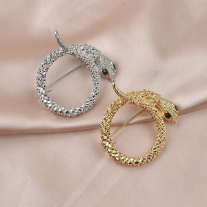 Detailed view of gold and silver snake brooches with black crystal eyes on pink silk