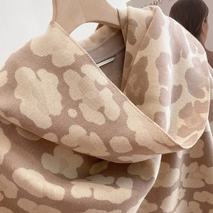 Close-up of thick beige leopard pattern cashmere feel scarf with soft knitted texture