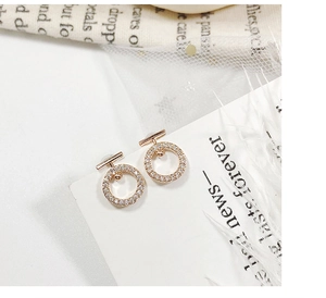 Close-up of rose gold circular drop earrings with shimmering pavé set zirconia stones