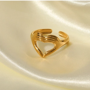 Detailed view of a gold-plated heart ring featuring a unique two-hands hugging gesture design