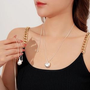 Détail de pendentifs cœur et goutte en argent mat brossé sur mannequin femme