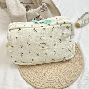 Detail of floral quilted makeup bag with green zipper and soft cotton texture