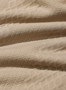 Macro shot of neutral beige jacquard fabric texture and textured weave on sweatshirt