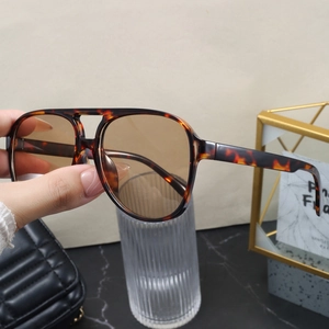 Detail of tortoise shell double-bridge pilot sunglasses held against a chic background